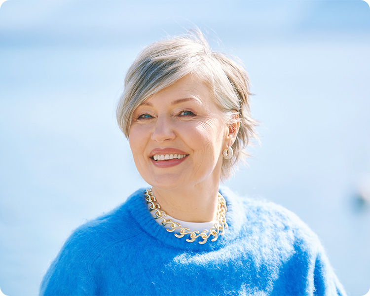 a woman in blue sweater looking at the camera and smile confidently